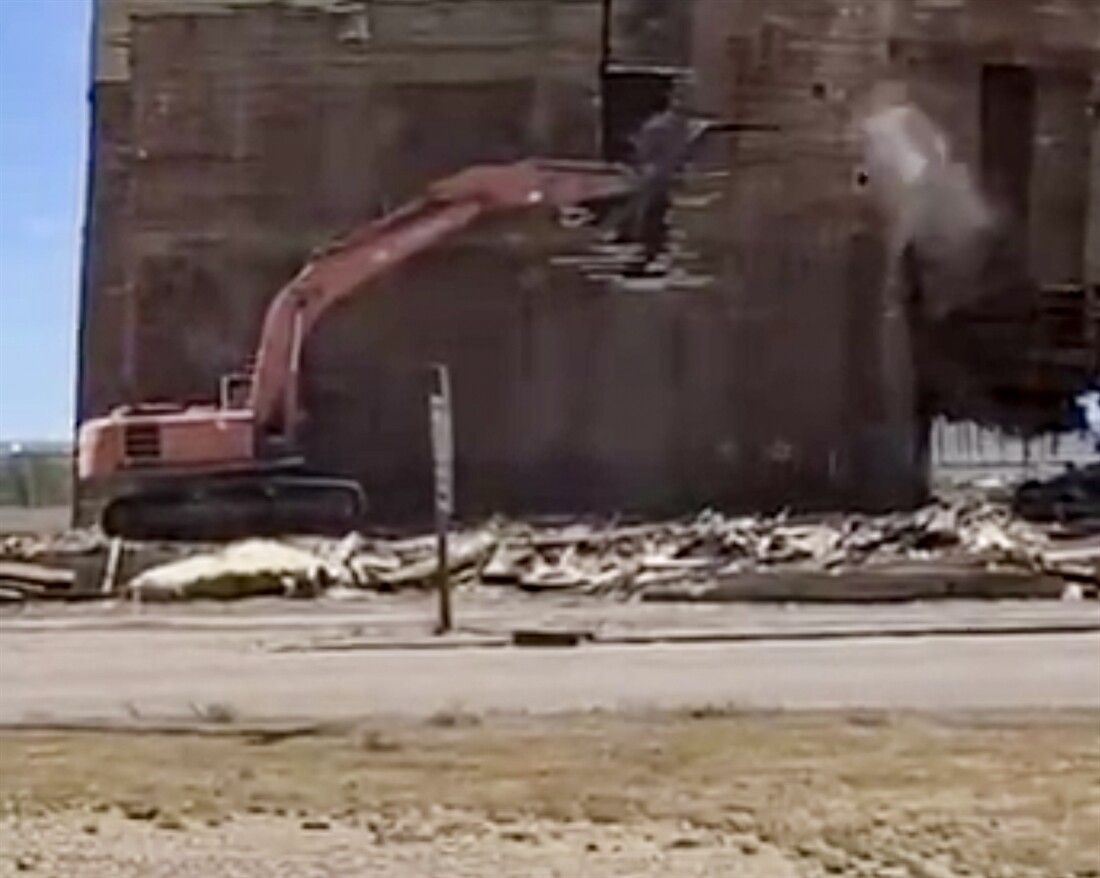 Excavator carries out risky demolition